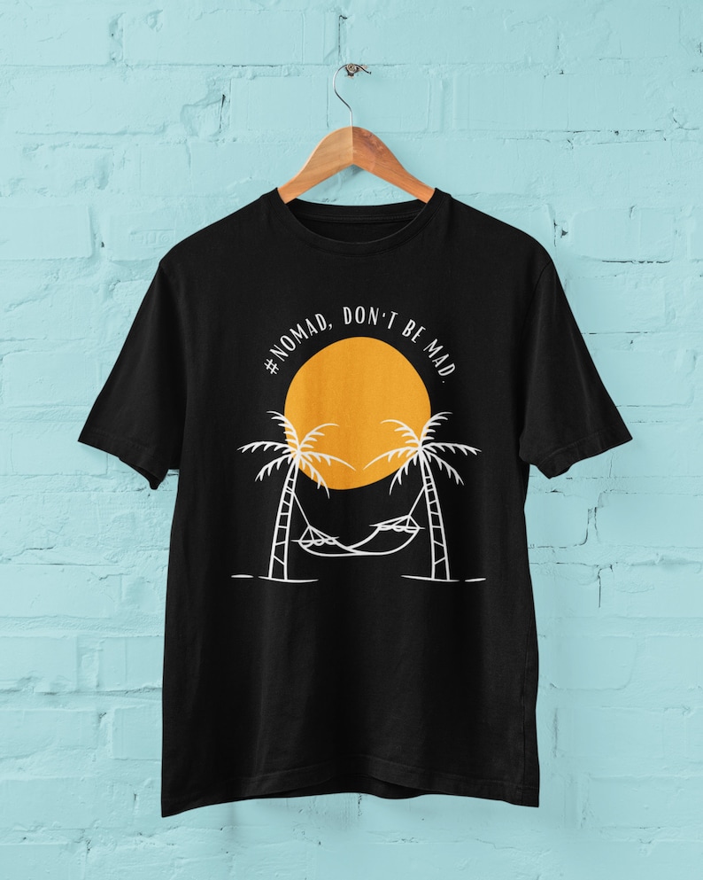 May include: Black t-shirt with a white graphic design of a hammock between two palm trees and a yellow sun with the text "#NOMAD. DON'T BE MAD."