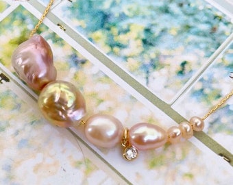 May include: A delicate gold chain necklace with a row of pink and white pearls and a small diamond pendant.