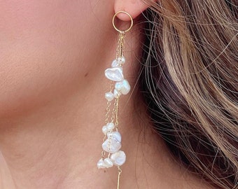 May include: Gold hoop earrings with a dangling chain and multiple white baroque pearls.