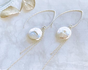 May include: A pair of silver earrings with a white pearl charm and a dangling chain.