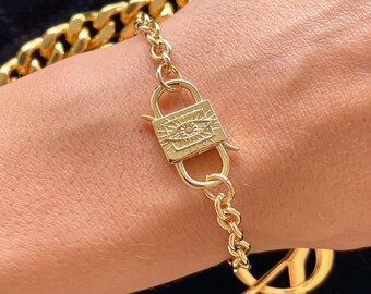 May include: Gold chain bracelet with a padlock clasp featuring an eye design.