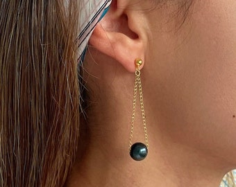 May include: Gold chain earrings with a black pearl dangling at the bottom.