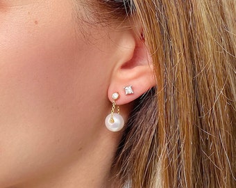 May include: A pair of gold earrings with a small diamond stud and a dangling pearl.