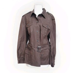 May include: Brown jacket with a belted waist, four front pockets, and button closures. The jacket has a collared neckline and epaulettes on the shoulders. The jacket is displayed on a white mannequin.