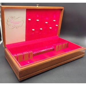 Może przedstawiać: Drewniana skrzynia na sztućce z czerwonym aksamitnym wnętrzem. Skrzynia ma etykietę z napisem "Reed & Barton Silverplate".