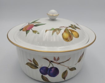 May include: White porcelain casserole dish with a lid, featuring a gold trim and a floral pattern with fruit. The pattern includes peaches, pears, and plums.