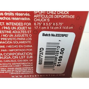 Pu&ograve; includere: Una scatola rossa e bianca con un codice a barre e testo che recita "Sport Chez Chuck" e "Art&iacute;culos Deportivos Chuck's". La scatola &egrave; etichettata con un numero di lotto, "Batch No. 0322SP02", e un prezzo di 159,00 &euro;. La scatola misura 17,1 cm per 14 cm per 14,6 cm.