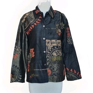 Può includere: Una camicia nera abbottonata con un design patchwork unico. La camicia presenta motivi intricati nelle tonalità dell'arancione, beige e verde. Il tessuto ha una lucentezza sottile e il design è visibile sulle maniche e sul davanti.