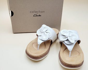 Sandali infradito Clarks da donna modello Brynn, taglia 5.5, in pelle bianca con fiore.