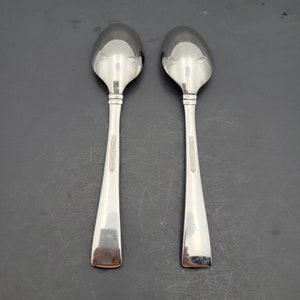 Op de afbeelding: Twee zilveren lepels met de woorden "Wallace Sterling" gegraveerd op de achterkant.