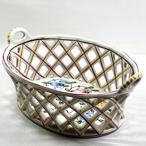 May include: White ceramic basket with a woven lattice design and floral accents in shades of blue, pink, and yellow.