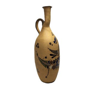 May include: Tan ceramic pitcher with a long neck and handle. The pitcher is decorated with a bird and floral design in blue, brown, and green. The pitcher has a textured surface.