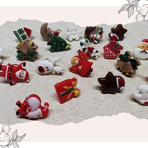 May include: A collection of miniature Christmas-themed figurines. The assortment includes Santa Claus, reindeer, Christmas trees, stars, and gift boxes. The figurines are in various colors, including red, white, green, and brown.