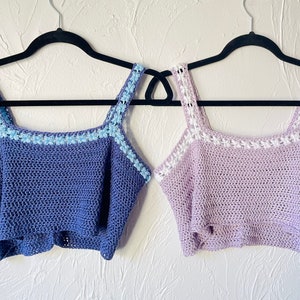 Könnte beinhalten: Zwei gehäkelte Tanktops, eines in hellblau mit weißem Besatz und das andere in helllila mit weißem Besatz.