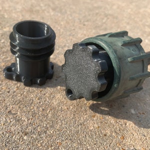 May include: A black plastic connector with a green outer ring and a black plastic cap. The connector has a threaded design and a small hole on the side.