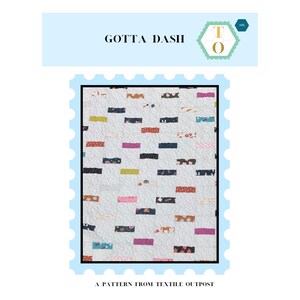 May include: A white quilt with a scattered pattern of colorful rectangular patches. The patches are in various colors, including pink, blue, green, and brown. The quilt has the text "GOTTA DASH" and "A PATTERN FROM TEXTILE OUTPOST".