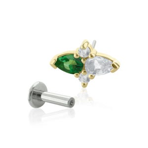 Puede incluir: Joyería de cuerpo dorada con un grupo de piedras preciosas verdes y blancas. La joyería es de estilo barra con un extremo roscado.