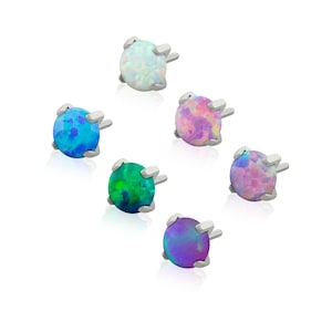 May include: A collection of six round stud earrings featuring iridescent opals in various colors including white, blue, green, pink, and purple. Each gemstone is set in a silver-toned metal prong setting with a post backing for secure attachment.