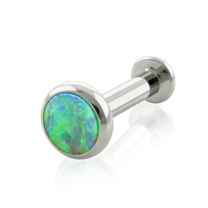 May include: A flat-back labret stud featuring a circular bezel setting with a polished silver-tone metal finish. The front face contains a round, iridescent synthetic opal stone displaying vibrant green and blue colour flashes throughout.