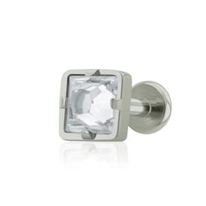 May include: A silver-toned stud earring with a square, clear crystal center. The crystal is set within a square frame, and the earring has a flat, round backing. The design is simple and elegant, suitable for various styles.