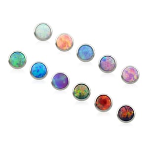 May include: A collection of ten circular stud earrings featuring cabochon-cut opals in various colors including white, orange, blue, purple, green, pink, and red. Each opal is set within a smooth, polished silver-toned metal bezel setting.
