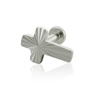 May include: A silver-colored, cross-shaped earring with a textured, radial design. The earring has a post and a small, round backing. The cross shape is the focal point, with a polished finish that reflects light.