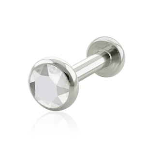 May include: A silver-toned labret stud body jewelry piece featuring a circular bezel setting with a clear, faceted, round-cut gemstone at the front and a smooth, flat, circular disc backing connected by a straight metal post.