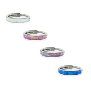 May include: Four circular hinged rings with a metallic finish, each featuring a different colored inlay. The top ring has a white inlay, the second a pink and orange inlay, the third a purple and blue inlay, and the bottom a bright blue inlay.