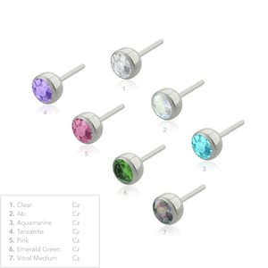 May include: Seven silver-toned stud earrings with round faceted stones in various colors, labeled 1 through 7. The colors include clear, AB, aquamarine, tanzanite, pink, emerald green, and vitral medium. Each earring features a straight post.