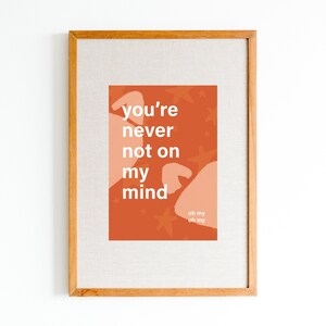Può includere: Una stampa incorniciata con uno sfondo arancione e testo bianco che recita "you're never not on my mind" con un testo più piccolo che recita "oh my oh my". Lo sfondo ha un motivo di stelle bianche e forme astratte color pesca.
