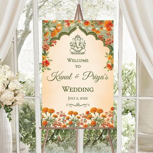 May include: A wedding welcome sign with a floral design featuring orange and green marigolds. The sign says "Welcome to Kunal & Priya's Wedding July 2, 202X".