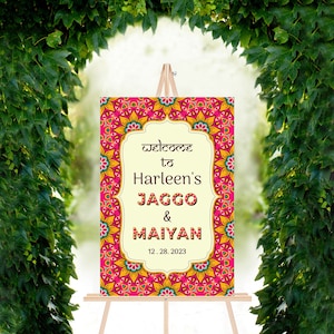 Pu&ograve; includere: Cartello di benvenuto per il matrimonio di Harleen's Jaggo & Maiyan con un design a mandala rosa, giallo e blu. La data 12.28.2023 &egrave; stampata sul cartello.