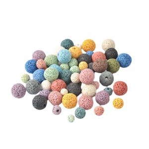 Peut inclure: Un ensemble de perles en roche volcanique colorées dans différentes nuances de bleu, vert, violet, rose, orange et marron. Les perles sont rondes et ont une texture poreuse.