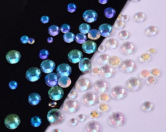 May include: An assortment of iridescent rhinestones in various sizes, scattered on a black and white background. The rhinestones display a range of colors, including blue, green, and clear, creating a sparkling effect. Ideal for craft projects and embellishments.