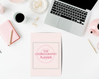 Op de afbeelding: Een roze en witte planner met de tekst "THE CHOREOGRAPHY PLANNER" in een cirkel op de omslag.
