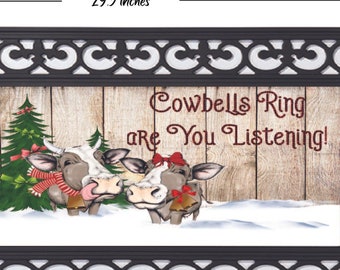May include: A black doormat with a white decorative border. The center of the mat features a winter scene with two cows and the text "Cowbells Ring are You Listening!" The mat measures 29.5 inches by 17.5 inches.