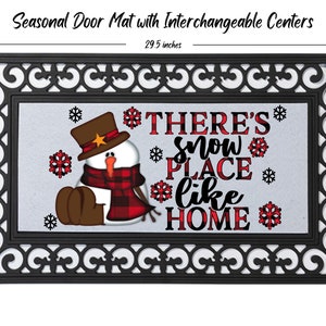 May include: A black doormat with a white border and a festive winter scene. The scene features a snowman wearing a red and black plaid scarf and a brown hat with a gold star. The text "THERE'S snow PLACE like HOME" is written in red and black plaid letters.
