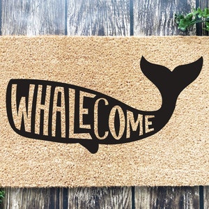 May include: A brown coir doormat with the word "WHALEcome" spelled out in a black whale silhouette.