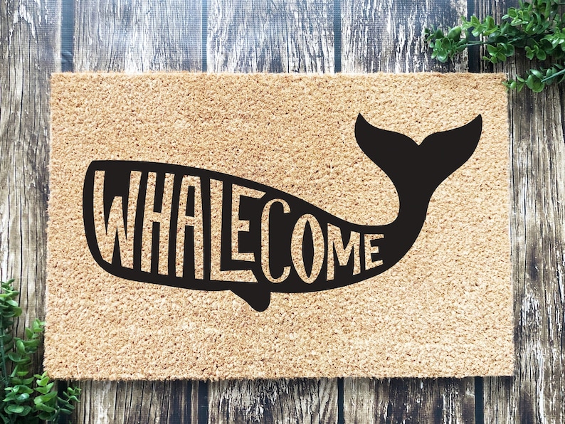 May include: A brown coir doormat with the word "WHALEcome" spelled out in a black whale silhouette.