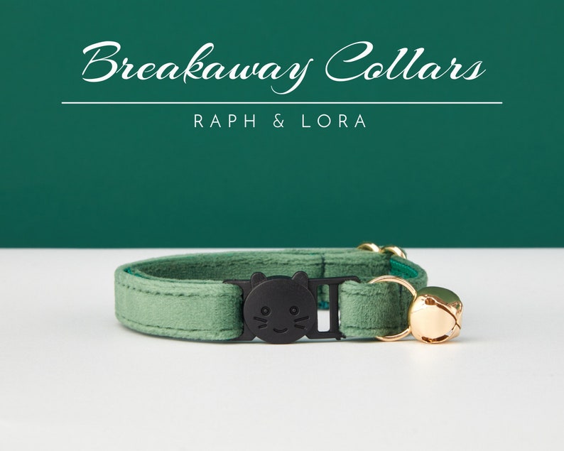 May include: A green velvet breakaway cat collar with a black cat face charm and a gold bell. The collar is on a white surface. Breakaway Collars, Raph & Lora.