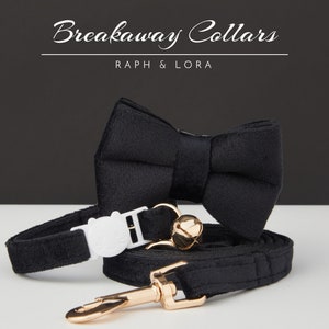 May include: Black velvet breakaway collar and matching bow tie for a pet. The collar has a white plastic buckle with a cat face design and a gold-colored metal clasp. The bow tie is made of black velvet and has a classic shape.