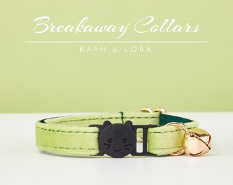 May include: A light green breakaway cat collar with a black cat face buckle and a gold bell. The collar is made of soft velvet and has a safety release buckle. The text "Breakaway Collars" and "Raph & Lora" is visible above the collar.