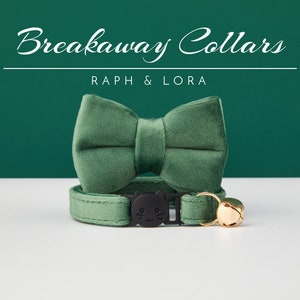 May include: A green velvet breakaway cat collar with a matching bow tie and a gold bell. The collar has a black plastic buckle with a cat face design. The text "Breakaway Collars" and "Raph & Lora" is printed above the collar.