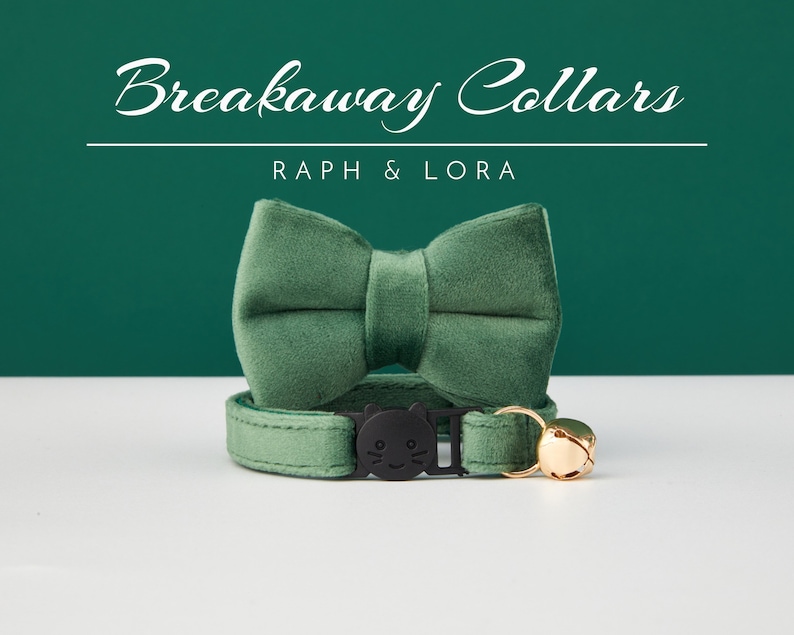 May include: A green velvet breakaway cat collar with a matching bow tie and a gold bell. The collar has a black plastic buckle with a cat face design. The text "Breakaway Collars" and "Raph & Lora" is printed above the collar.
