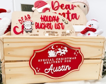 May include: A wooden crate with a red and gold sign that reads "Special Christmas Delivery for Austin." Inside are holiday-themed decorations, including a Santa hat, a snowman, and a "Dear Santa" sign with a bucket list.