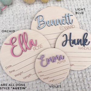 Four wooden name plaques in various sizes, each with a different name in a cursive font. The names are in light blue, orchid, navy, and violet. Each plaque has lines for recording birth details. The text "THESE ARE ALL DONE IN THE STYLE "AUSTIN"" is at the bottom.