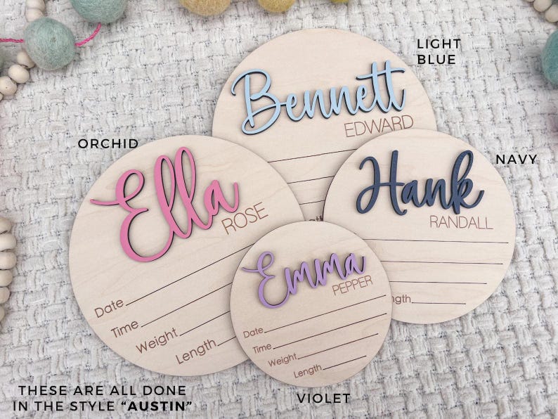 Four wooden name plaques in various sizes, each with a different name in a cursive font. The names are in light blue, orchid, navy, and violet. Each plaque has lines for recording birth details. The text "THESE ARE ALL DONE IN THE STYLE "AUSTIN"" is at the bottom.