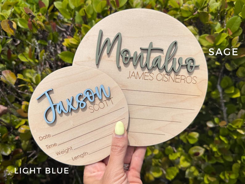 Two wooden round name plaque showing in different sizess.  Smal sign is 5" showing light blue 3D name and the bigger one is 6" showing 3D name in color sage.