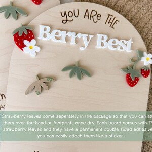 May include: Wooden plaque with the phrase "You Are The Berry Best" in white letters. The plaque is decorated with red strawberries, white flowers, and green leaves. A cute and cheerful design.