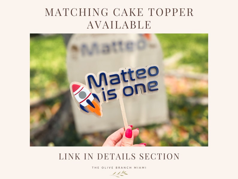 Pu&ograve; includere: Un topper per torta blu e bianco con un razzo e il testo "Matteo ha un anno".